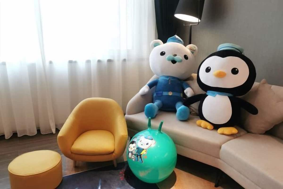 Una sala de estar con un sofá, un sillón amarillo y una pelota de ejercicios verde.