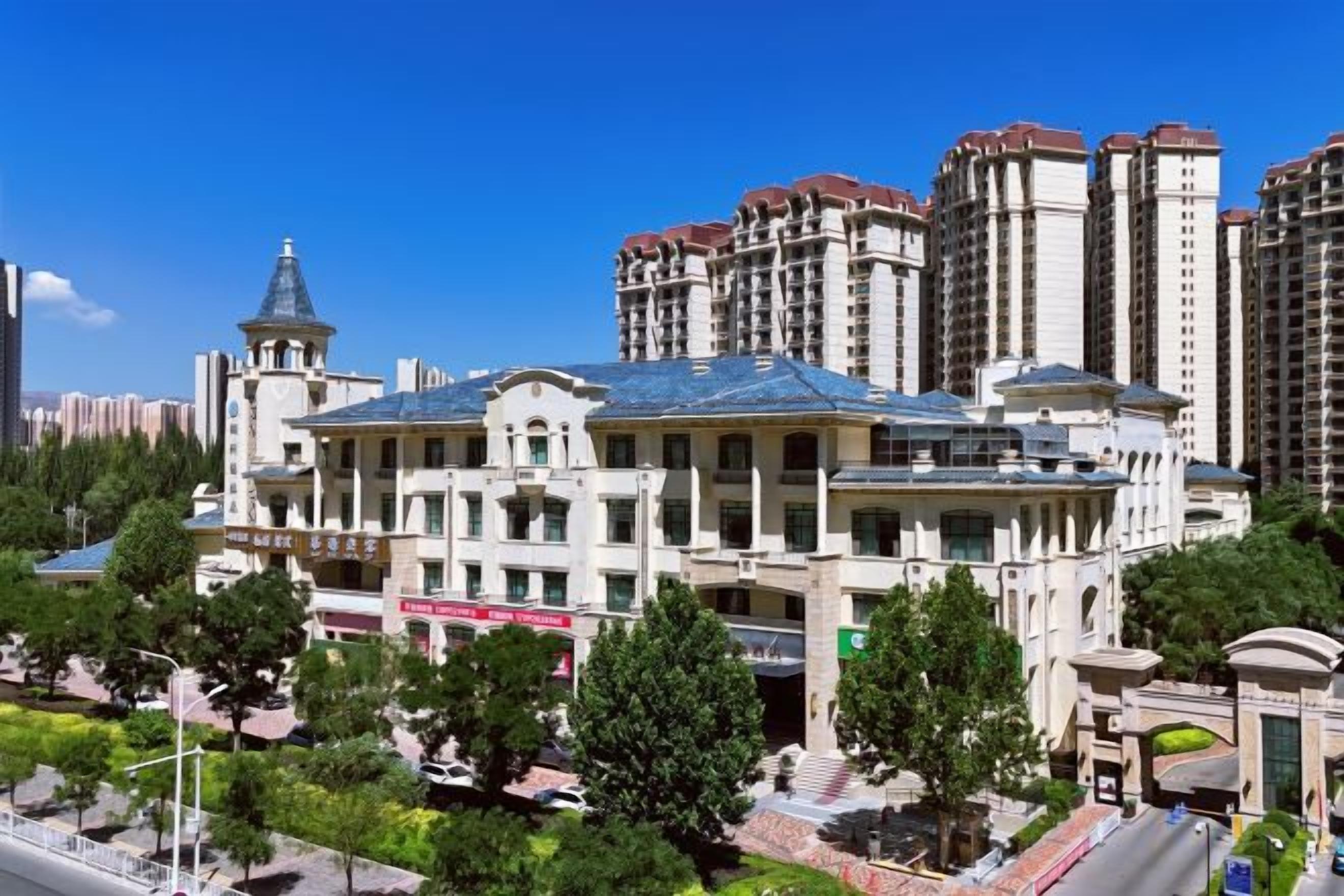 A large, historic building with a prominent dome and tower, surrounded by modern high-rise buildings.