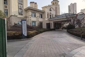 Une entrée d’immeuble avec une allée pavée menant à un espace d’entrée abrité.