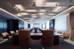 A conference room with a long table, multiple chairs, and a modern ceiling design.