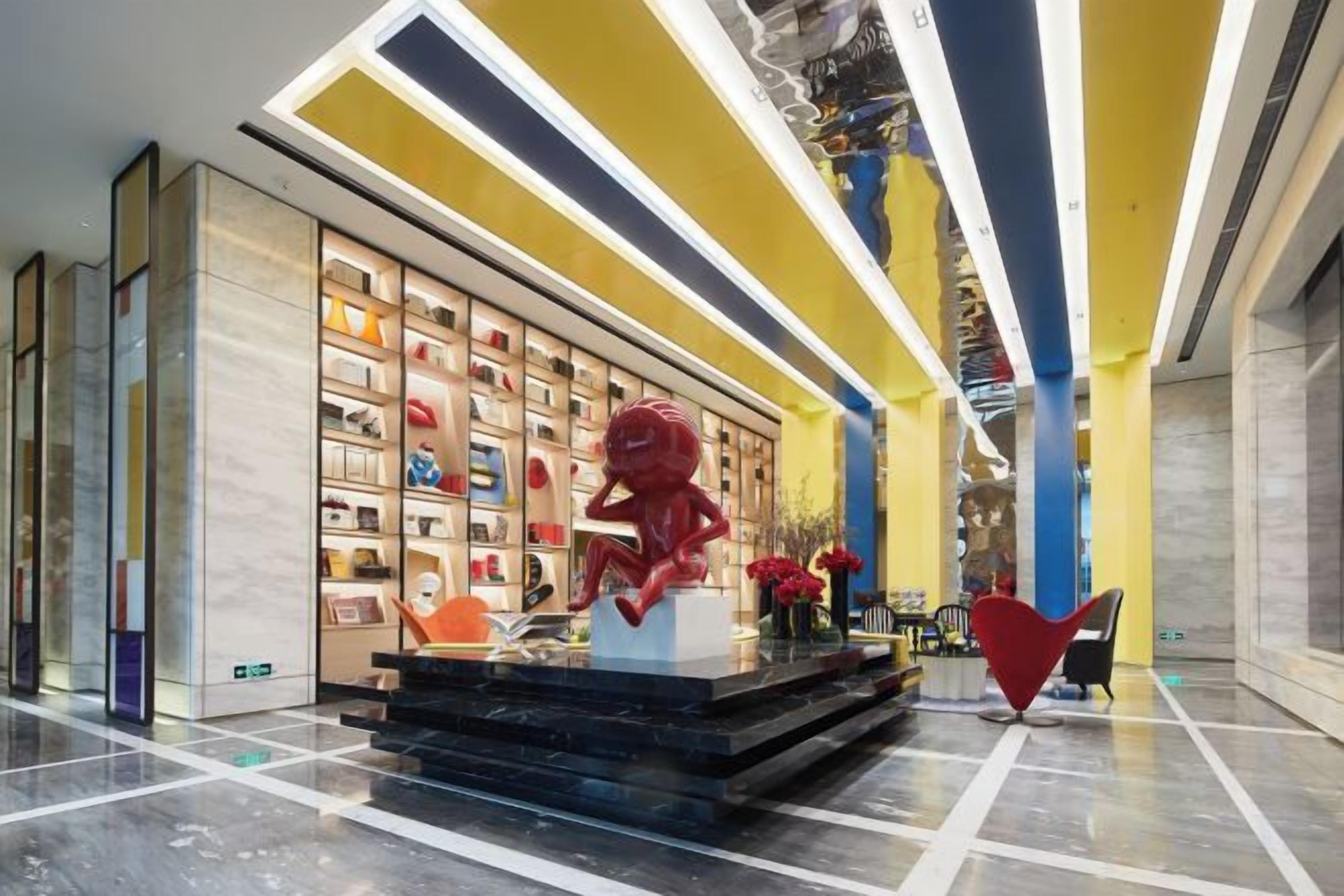 Un vestíbulo moderno con una escultura central, una estantería y un diseño de sillón único.