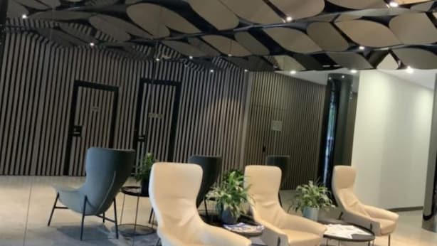 Un interior moderno con un diseño de techo único, zonas de estar y listones verticales de madera en las paredes.
