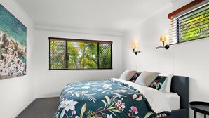 Ein Schlafzimmer mit einem Bett, einem Fenster mit Aussicht und einer Wandleuchte.