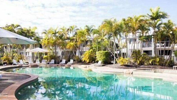 Ein Swimmingpool, umgeben von Palmen und Liegestühlen.