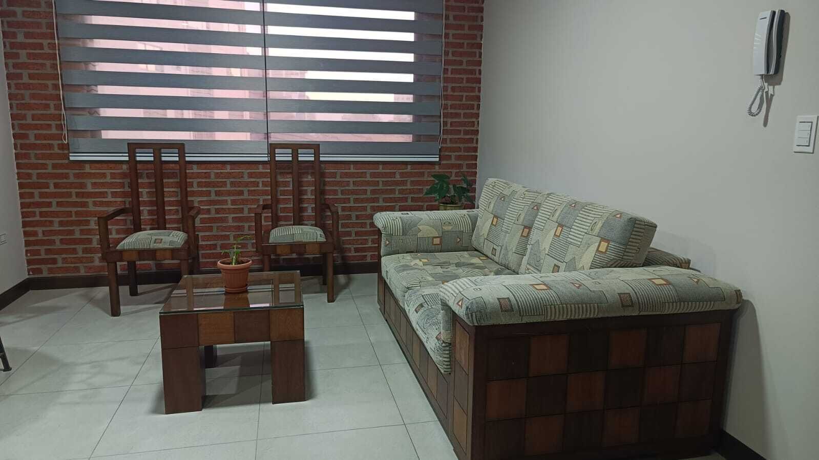 A living room with a sofa, two chairs, a coffee table, and a potted plant.