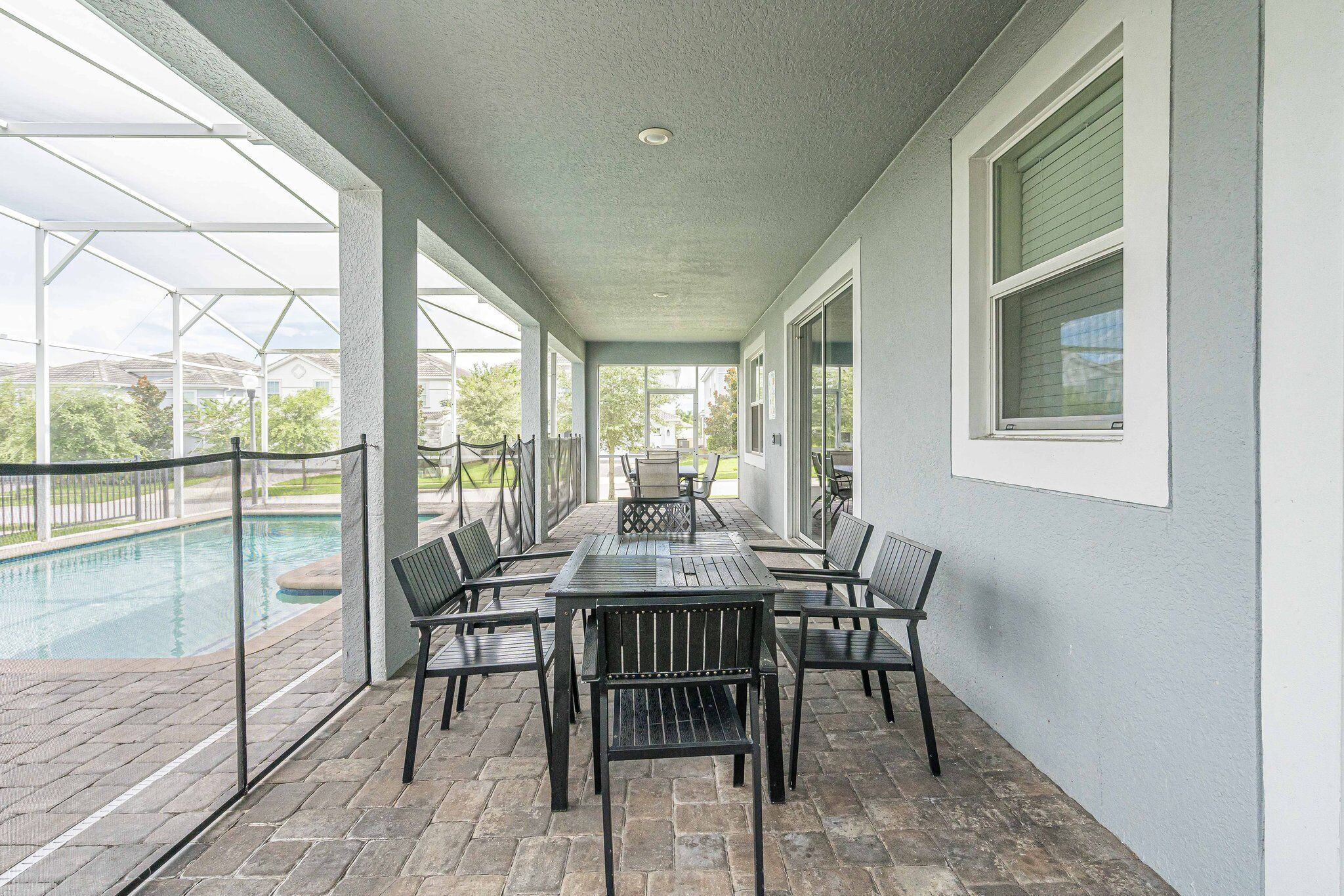 A covered patio area with a pool, outdoor seating, and large windows.