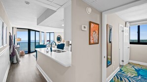 A modern kitchen with a white countertop, a sink, and a view of the ocean.