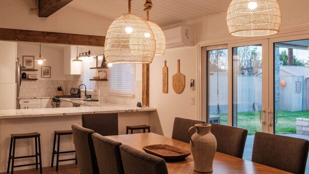 Une cuisine moderne dotée d’un îlot central, de luminaires suspendus et d’un coin repas avec une table et des chaises.