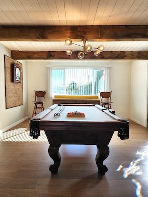 Relax in a spacious room with a pool table, comfortable seating, and a large window.