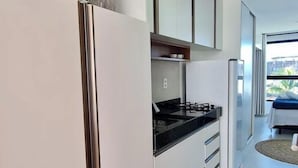 A modern kitchen with white cabinetry, a black stovetop, and a built-in oven. - Villas do Porto - 212 by La Playa (Ipojuca)