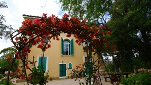 A building with a garden, a gravel path, and a bench. - Eucalyptus Apartment 3 (Porto Azzurro)