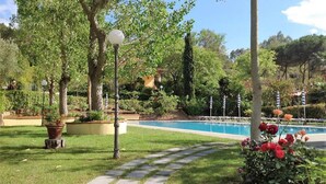 A garden with a pool, stone pathway, and potted plants. - Eucalyptus Apartment 3 (Porto Azzurro)