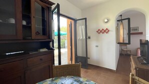 A room with a dining table, chairs, a cabinet, and a sliding glass door leading to an outdoor area.