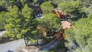 A hillside property with a red-roofed building, a paved driveway, and a parking area.