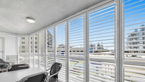 A room with a large window, a table, chairs, and a ceiling light. - Beachside Apartment (Sunshine Coast)