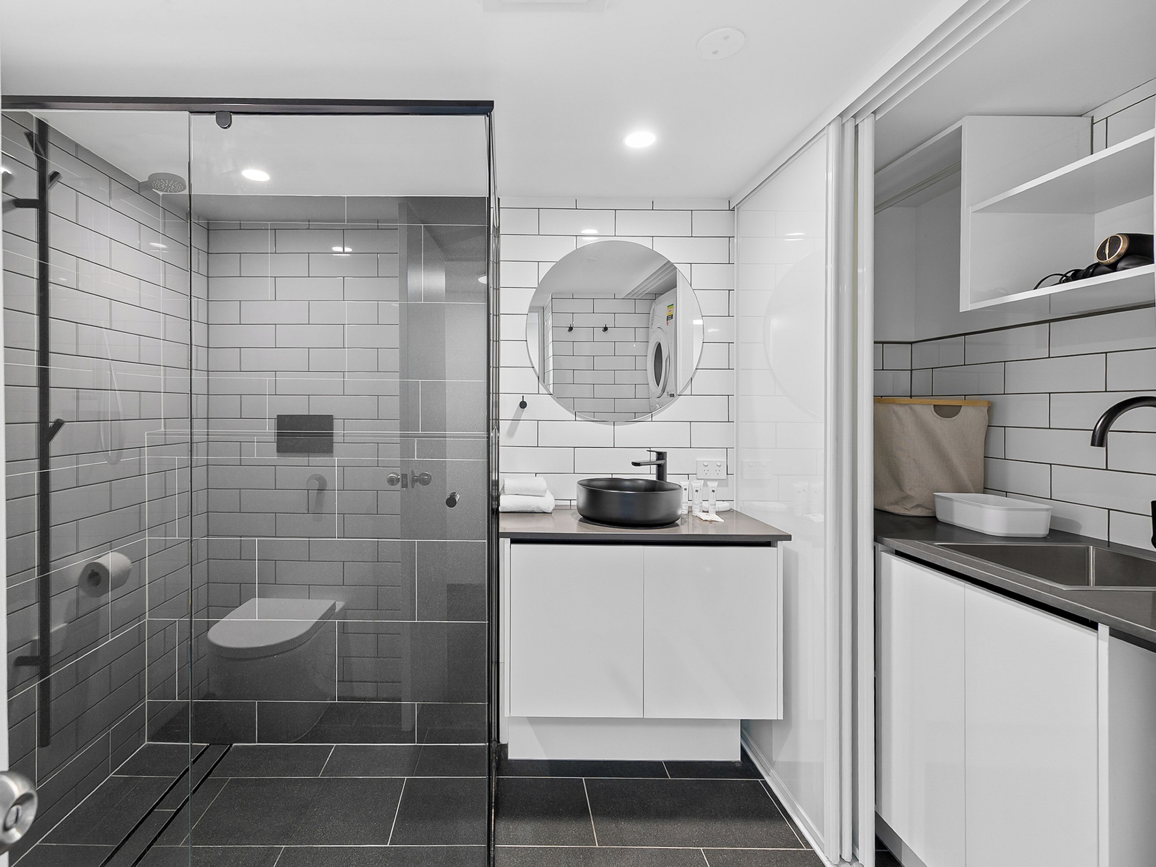 A modern bathroom with a glass-enclosed shower, a sink with a mirror, and a toilet.