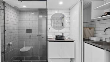 A modern bathroom with a glass-enclosed shower, a sink with a mirror, and a toilet.