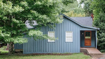 A small, single-story house with a blue exterior, a wooden front door, and a small porch.