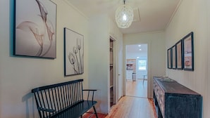 A hallway with a wooden bench, a dark wooden dresser, and framed artwork on the walls. - Bluebird Cottage: Near 151 + Appalachian Trail (Roseland)
