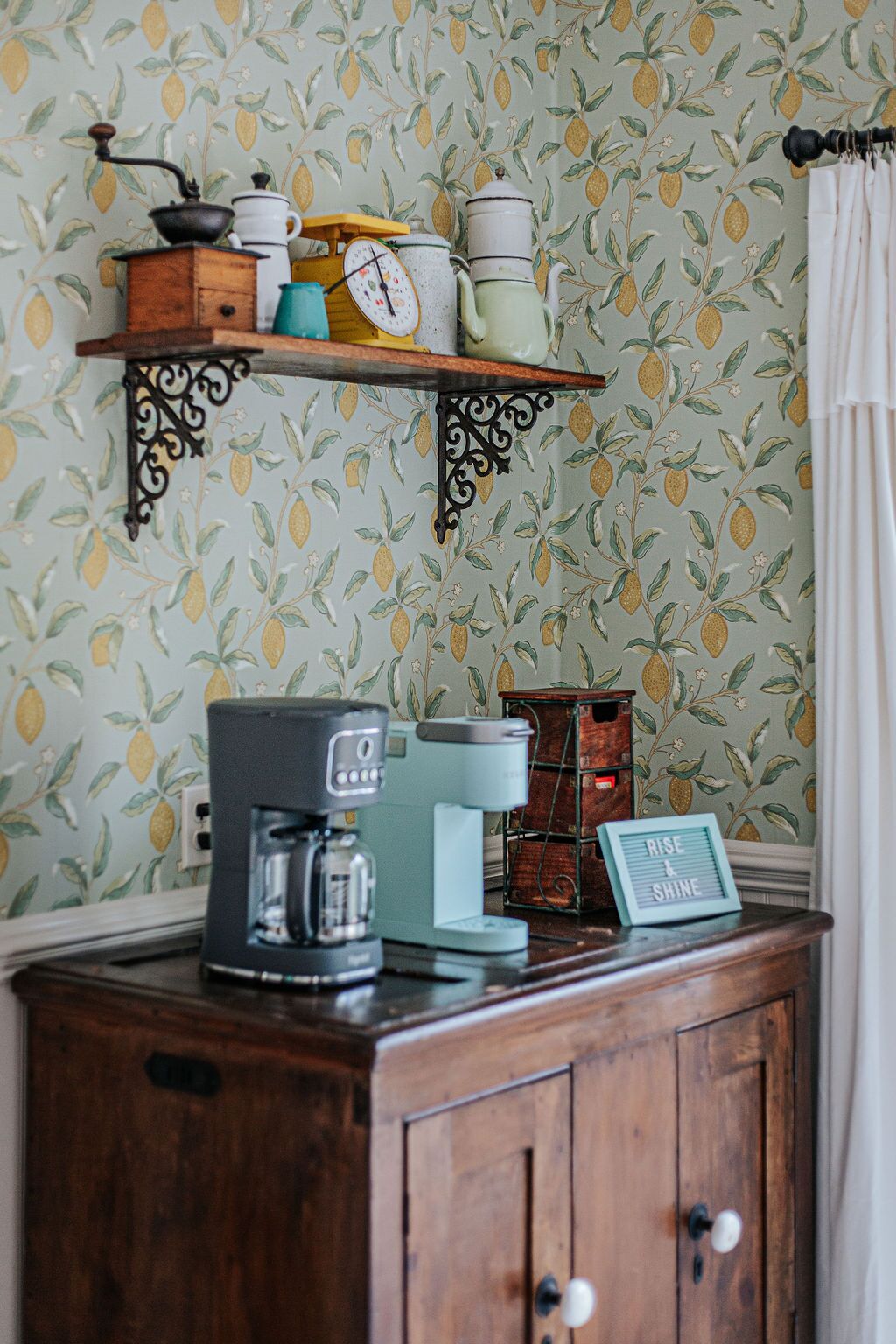 Una cocina con cafetera, balanza y un estante de estilo vintage con utensilios de cocina.