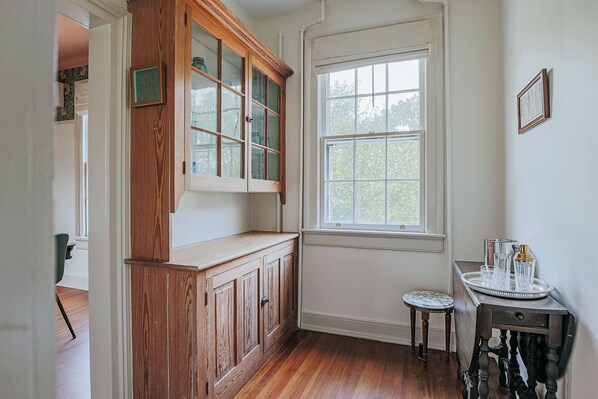 Ein Zimmer mit Holzschränken, einem Fenster und einem kleinen Tisch mit Tablett.