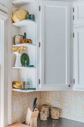 Une cuisine avec des meubles blancs, une horloge et des objets décoratifs disposés sur des étagères.