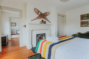 Un dormitorio con chimenea, una cama con colcha a rayas y un adorno en la pared.