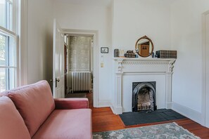 Ein Zimmer mit Kamin, einem roten Sofa und einem gemusterten Teppich.