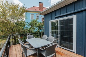 Una terrazza con tavolo e sedie, una porta scorrevole in vetro e vista su una casa blu.