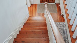 Un escalier en bois, avec des balustrades blanches, mène à une porte en bois.