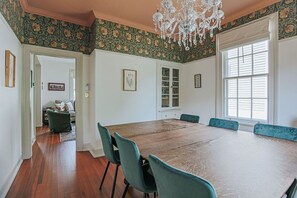 Ein Esszimmer mit einem großen Holztisch, blaugrünen Stühlen und einer Kronleuchter.