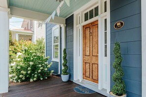 Ein Haus mit einer Holztür, blau gestrichenen Außenwänden und einer Fußmatte mit der Aufschrift 'hello'.