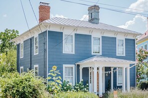 Une maison à deux étages avec un toit à pignon, une véranda et une cheminée.