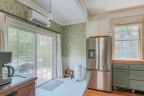 A kitchen with a stainless steel refrigerator, white cabinets, and a window with a view of greenery. - The Woodward: Walk Downtown, Staunton Mural (Staunton)