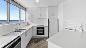 A modern kitchen with white cabinetry, a built-in oven, and a dishwasher.