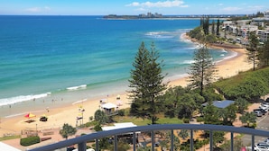 A coastal view with a beach, ocean, and buildings in the background.