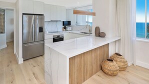 A modern kitchen with a large island, stainless steel appliances, and a view of the ocean.