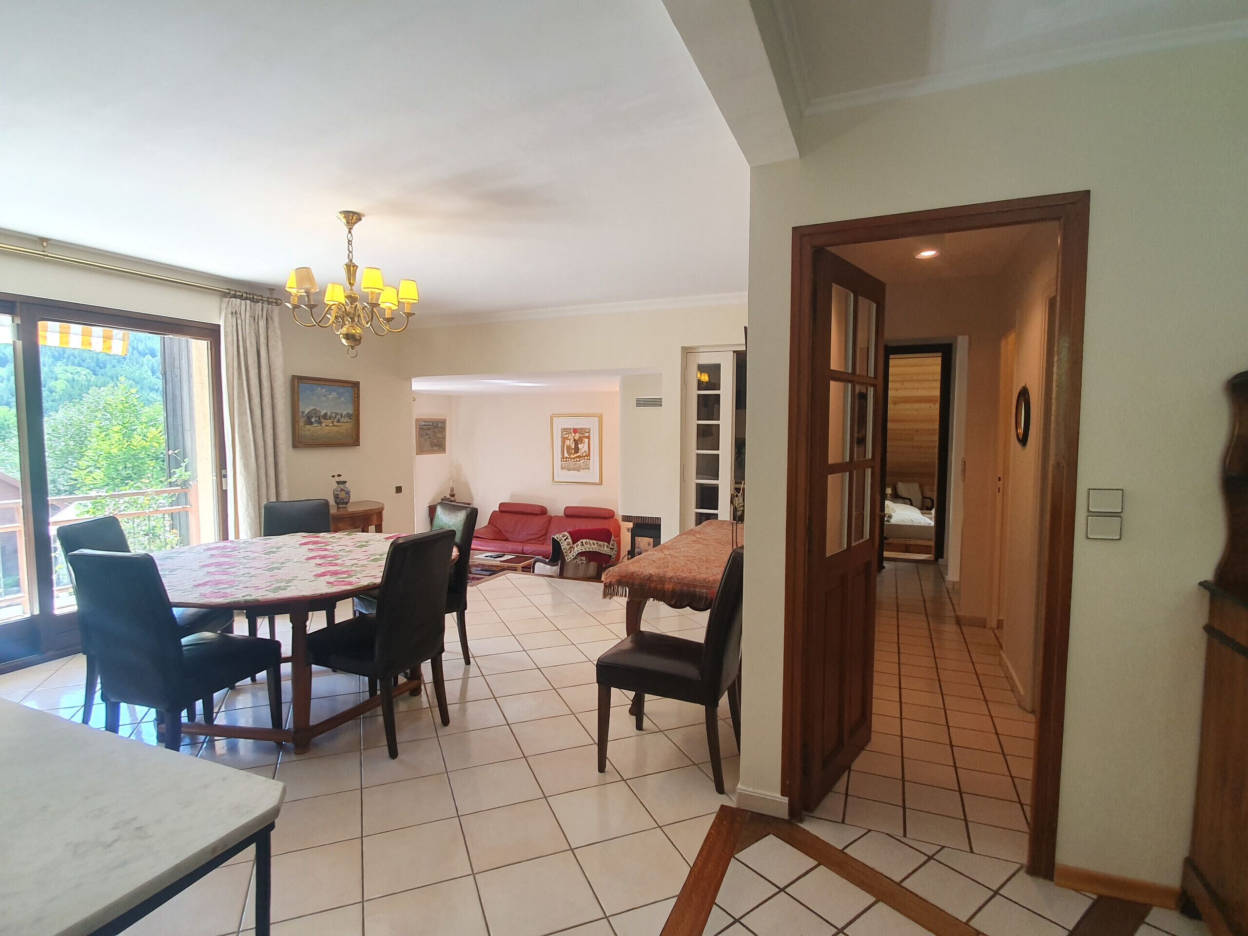 Uma área de refeições com mesa e cadeiras, um sofá vermelho e um candelabro.
