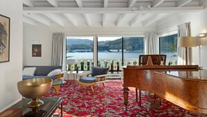 A spacious room with a grand piano, a sofa, and a view of a lake.