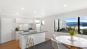 A modern kitchen with white cabinets, a central island, and a dining area with a table and chairs.