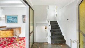 A staircase with a dark carpeted floor leading to a landing, white walls, and a door with a brass handle.