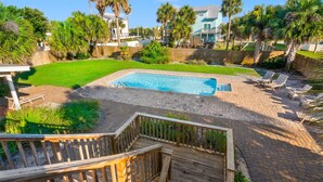 A backyard with a swimming pool, wooden deck, and lounge chairs.
