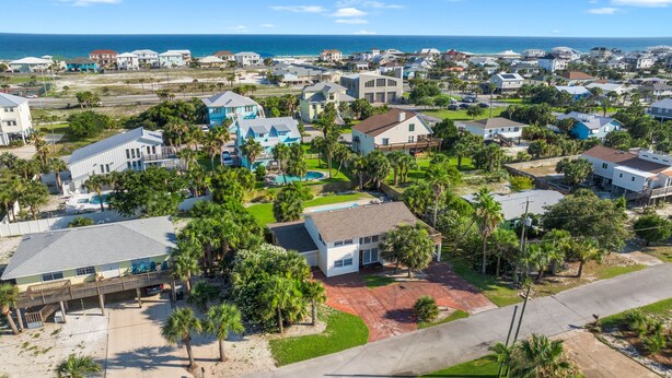 A residential area with houses, a swimming pool, and a beach in the background.