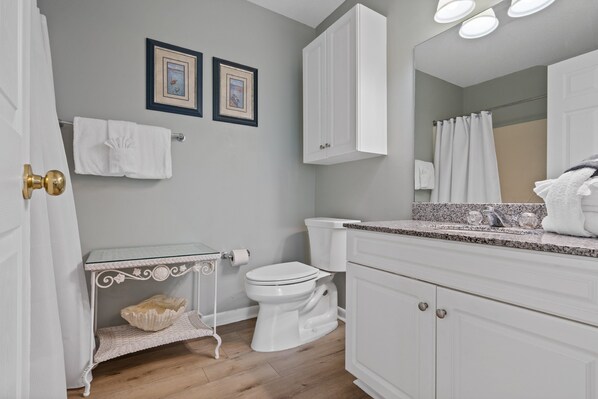 Une salle de bain comprenant des toilettes, un meuble-lavabo avec un miroir et deux tableaux encadrés accrochés au mur.