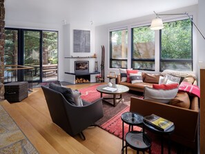 A modern living room with a fireplace, large windows, and a cozy seating area. - RMR: Tram Tower 5 Condo in Teton Village (Teton Village)