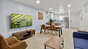 Ein modernes Wohnzimmer mit einem Flachbildfernseher, einem Holztisch und einem blauen Sofa.