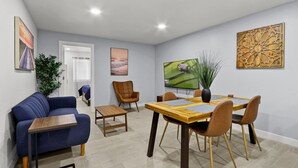 Ein modernes Wohnzimmer mit einem blauen Sofa, einem Holztisch und einem Essbereich mit Tisch und Stühlen.