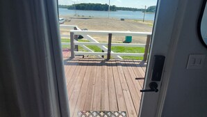Une vue depuis une porte donnant sur une terrasse, avec un paillasson, un drapeau américain et une plage en arrière-plan.