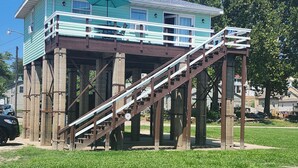 Une maison dotée d’une terrasse en bois et d’un escalier menant à un deuxième étage.