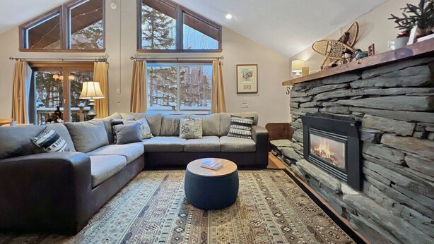 Una sala de estar acogedora con chimenea de piedra, un ventanal grande y un sofá modular.